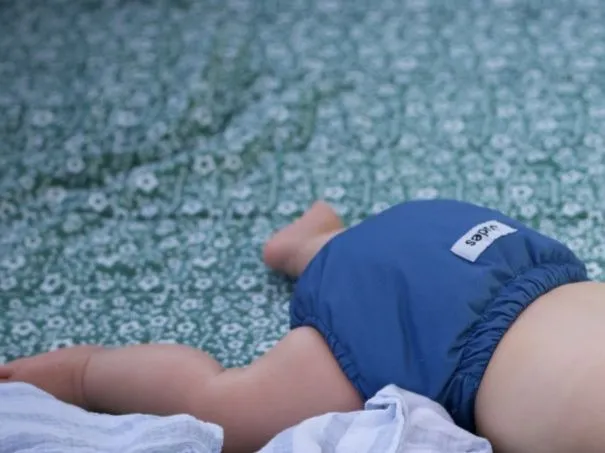 Baby mit blauer Stoffwindel auf einer Decke